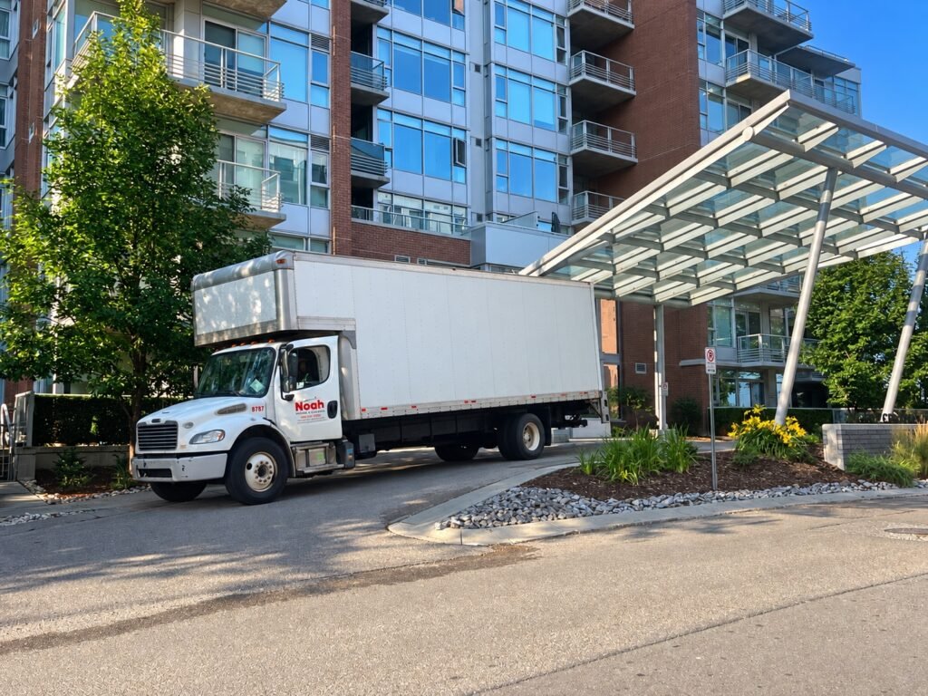 Noah Moving & Cleaning truck parked outside a multi-unit residential building