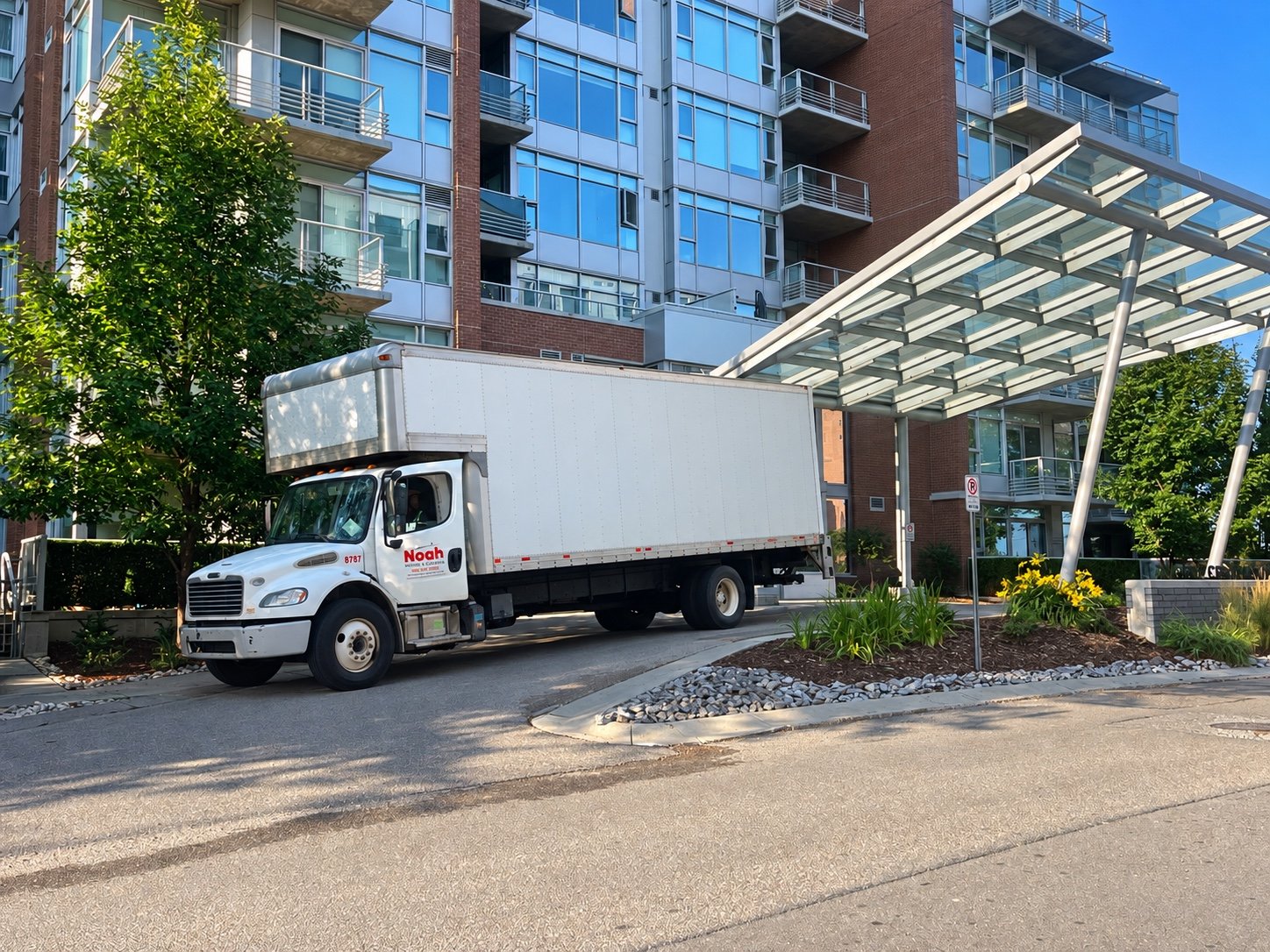 Noah Moving & Cleaning truck parked outside a multi-unit residential building